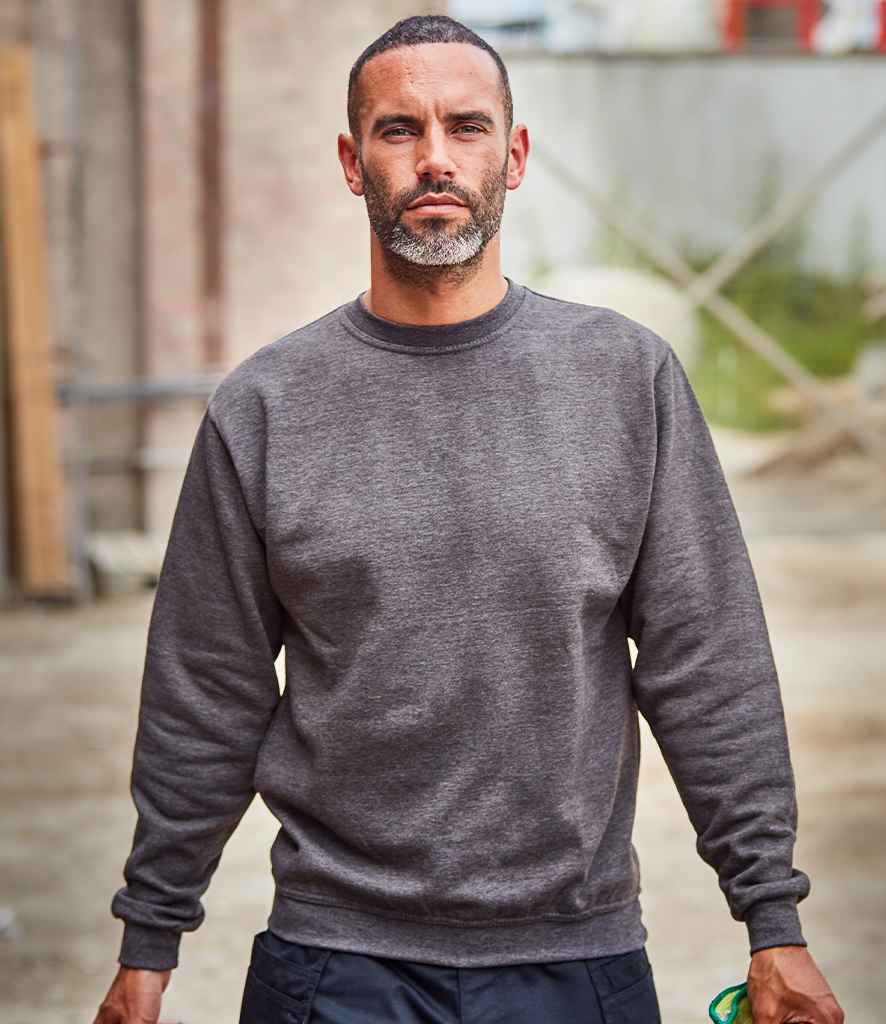 A man wearing a gray sweatshirt and dark pants, standing with one hand in his pocket and the other extended forward.